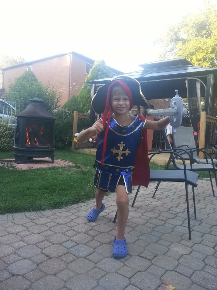 Young knight in costume with foam sword training in the backyard during a medieval-themed birthday party